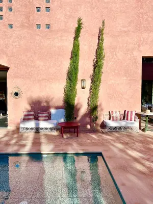 a patio with chairs and a pool in front of a building at Palais Celeste in Marrakech