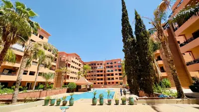 a resort with a swimming pool and palm trees and buildings at Résidence Babylone Y - 2 Bedrooms Appartement in Marrakech