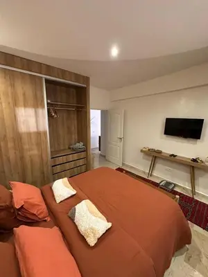 a bedroom with a large bed and a flat screen tv at J40 super bien équipé a L'HIVERNAGE in Marrakech