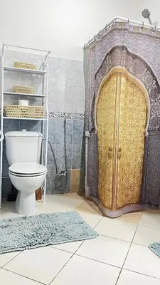 a bathroom with a toilet and a gold door at charmant appartement Marrakech in Marrakech