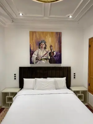 a bedroom with a bed with a painting on the wall at Riad Casa Maria in Marrakech