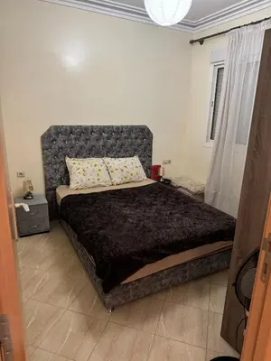 a bedroom with a large bed with a gray headboard at A bright and airy living room in Marrakech