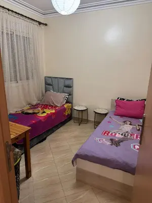 a bedroom with two beds and a table and a window at A bright and airy living room in Marrakech