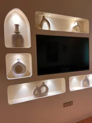 a flat screen tv on a wall with shelves at Riad Appart F3 Exceptionnel à Guéliz - À 5 min de la gare - Piscine, Wi-Fi et parking au cœur de Marrakech in Marrakech