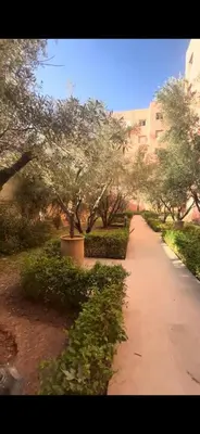 a path in a park with trees and a building at Riad Appart F3 Exceptionnel à Guéliz - À 5 min de la gare - Piscine, Wi-Fi et parking au cœur de Marrakech in Marrakech
