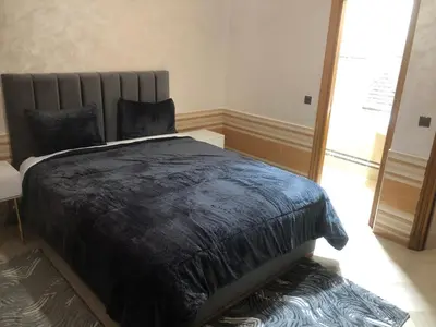 a bedroom with a black comforter on a bed at Résidence Babylone Y - Appartement 2 Chambres in Marrakech