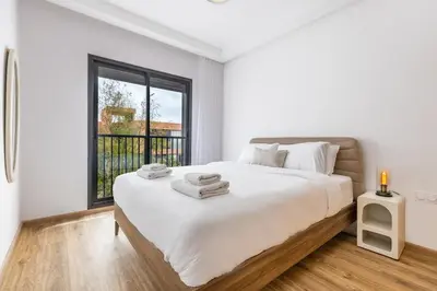 a white bedroom with a large bed and a window at Escapade relaxante au Domaine NORIA in Marrakech