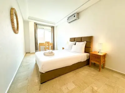 a bedroom with a bed and a table and a window at Elegant 2-Bedroom Duplex Downtown Private Terrace in Marrakech