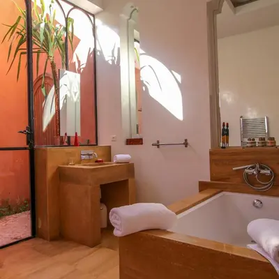 a bathroom with a tub and a sink and a mirror at Villa Jardin Nomade in Marrakech
