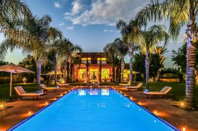 a swimming pool with palm trees and a house at Villa Jardin Nomade in Marrakech