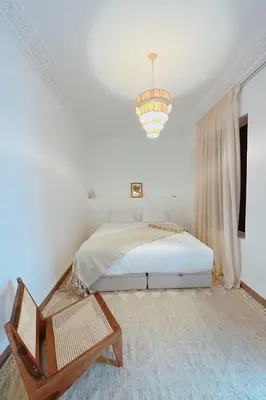 a white bedroom with a bed and a chandelier at Riad Solila, Fabuleux riad avec 4 Suites, Piscine Chauffée et Rooftop - 5 min de Jamaa El Fna in Marrakech