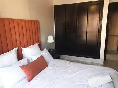 a bedroom with a white bed with a large television at In Gueliz, Chic and Ethnic with a palm view in Marrakech