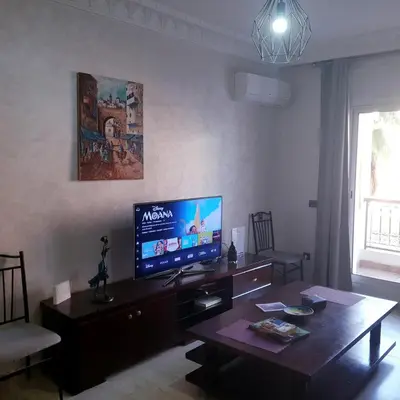 a living room with a table and a flat screen tv at In Gueliz, Chic and Ethnic with a palm view in Marrakech