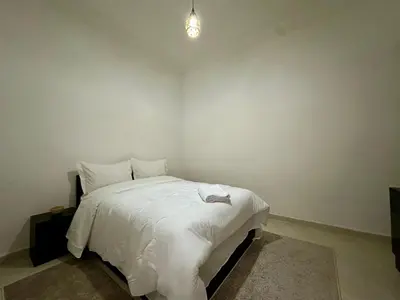 a bedroom with a bed with white sheets and a light at Modern & Chic Duplex Near The Center, Brand New in Marrakech