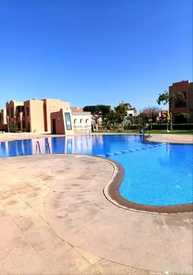 an empty swimming pool with blue water and buildings at Appartement Belle vue sur l'atlas in Marrakech