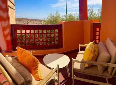 a room with chairs and a table and a balcony at Appartement Belle vue sur l'atlas in Marrakech
