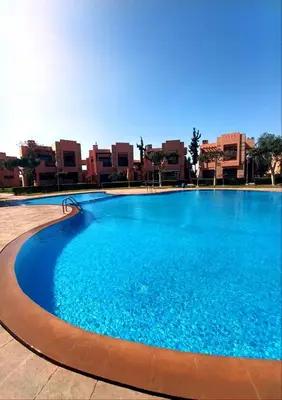a large blue swimming pool with buildings in the background at Appartement Belle vue sur l'atlas in Marrakech