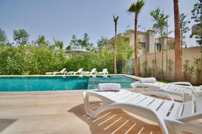 a swimming pool with white lounge chairs next to a resort at Villa Luxe 5 Suites & Piscine in Marrakech