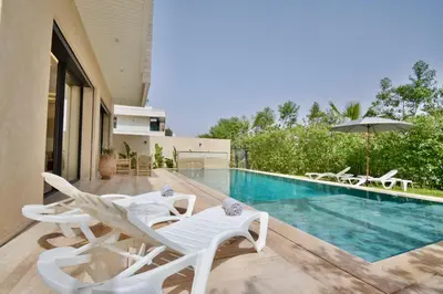 a swimming pool with white lounge chairs and an umbrella at Villa Luxe 5 Suites & Piscine in Marrakech