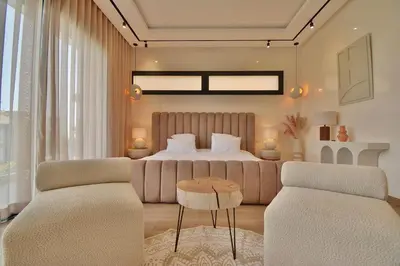 a bedroom with a bed and two chairs and a table at Villa Luxe 5 Suites & Piscine in Marrakech