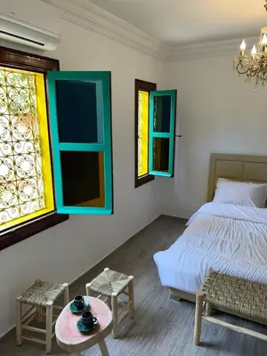 a bedroom with a bed and a table and windows at Riad For families and groups in Marrakech