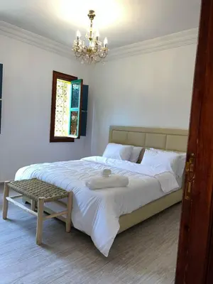 a bedroom with a large bed with a chandelier at Riad For families and groups in Marrakech
