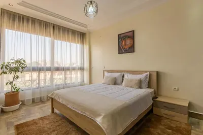 a bedroom with a bed and a large window at ELEGANT APARTMENT DOWNTOWN m in Marrakech