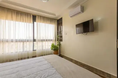 a bedroom with a bed and a tv on the wall at ELEGANT APARTMENT DOWNTOWN m in Marrakech