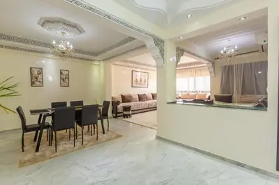 a dining room with a table and chairs and a couch at ELEGANT APARTMENT DOWNTOWN m in Marrakech