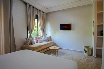 a room with a bed and a couch and a window at Villa Dar Cactus piscine chauffée in Marrakech