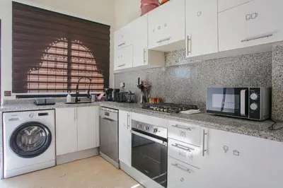 a kitchen with white cabinets and a washer and dryer at Villa Dar Cactus piscine chauffée in Marrakech