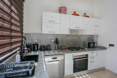 a kitchen with white cabinets and a stove top oven at Villa Dar Cactus piscine chauffée in Marrakech