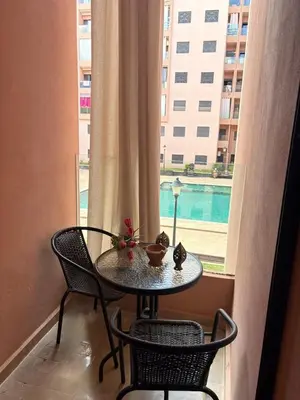 a table and chairs in a room with a window at Appartement Vue sur piscine in Marrakech