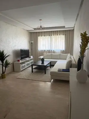 a living room with a couch and a tv at Appartement Vue sur piscine in Marrakech