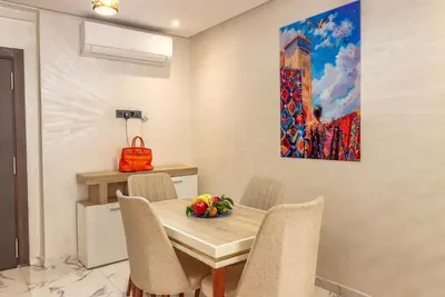 a dining room with a table and a painting on the wall at Piscine- Résidence haut de Gamme in Marrakech