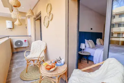 a room with a balcony with a bed and a table at Piscine- Résidence haut de Gamme in Marrakech