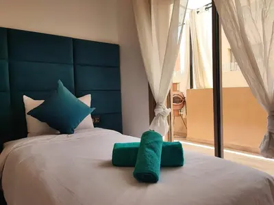 a bed with green towels on it with a window at Stylish Apartment with Pool in Central Location Near Gueliz and Medina in Marrakech