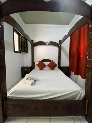 a bedroom with a wooden bed with red pillows at Riad Zitoune in Marrakech