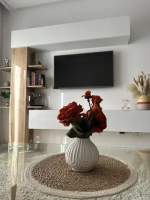 a white vase with red flowers in a living room at Luxury apartment and free parking in Marrakech