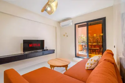 a living room with an orange couch and a tv at Exclusive Family Appartement in Marrakech