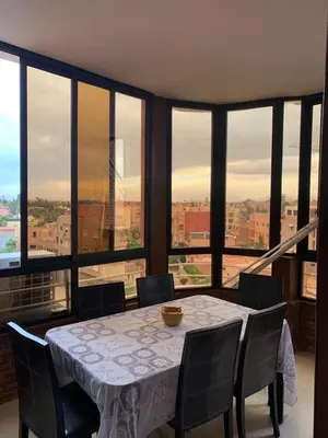 a dining room with a table and chairs and a large window at Asmae in Marrakech