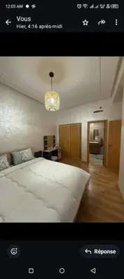 a bedroom with a large white bed and a chandelier at Spacieux appartement familial 2 in Marrakech