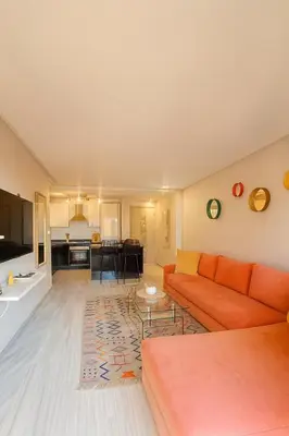 a living room with an orange couch and a kitchen at Chic 1 bedroom WiFi apartment Marrakech in Marrakech
