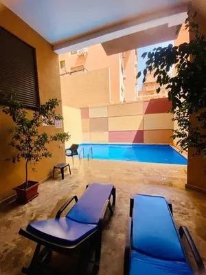a swimming pool with two blue chairs in a building at A21 Moderne Confort Au Cœur De Marrakech in Marrakech