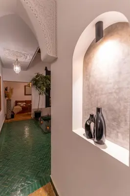 a hallway with a green floor and a wall with a vase at Riad OM SAADENE in Marrakech