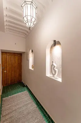 a hallway with a wooden door and a chandelier at Riad OM SAADENE in Marrakech
