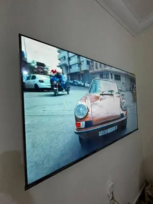 a tv hanging on a wall with a picture of a car at Modern Apartment Near Airport in Marrakech