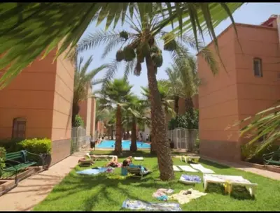 a group of people laying on the grass under palm trees at Riad Ibrahim in Marrakech