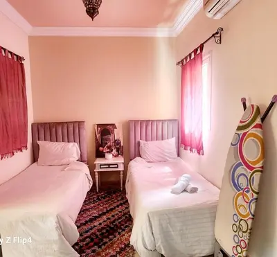 two beds in a room with pink curtains at Riad Ibrahim in Marrakech
