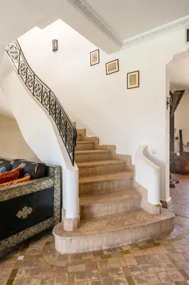a staircase in a home with white walls and wooden floors at Beautiful villa with a private pool in La Palmeraie neighborhood in Marrakech